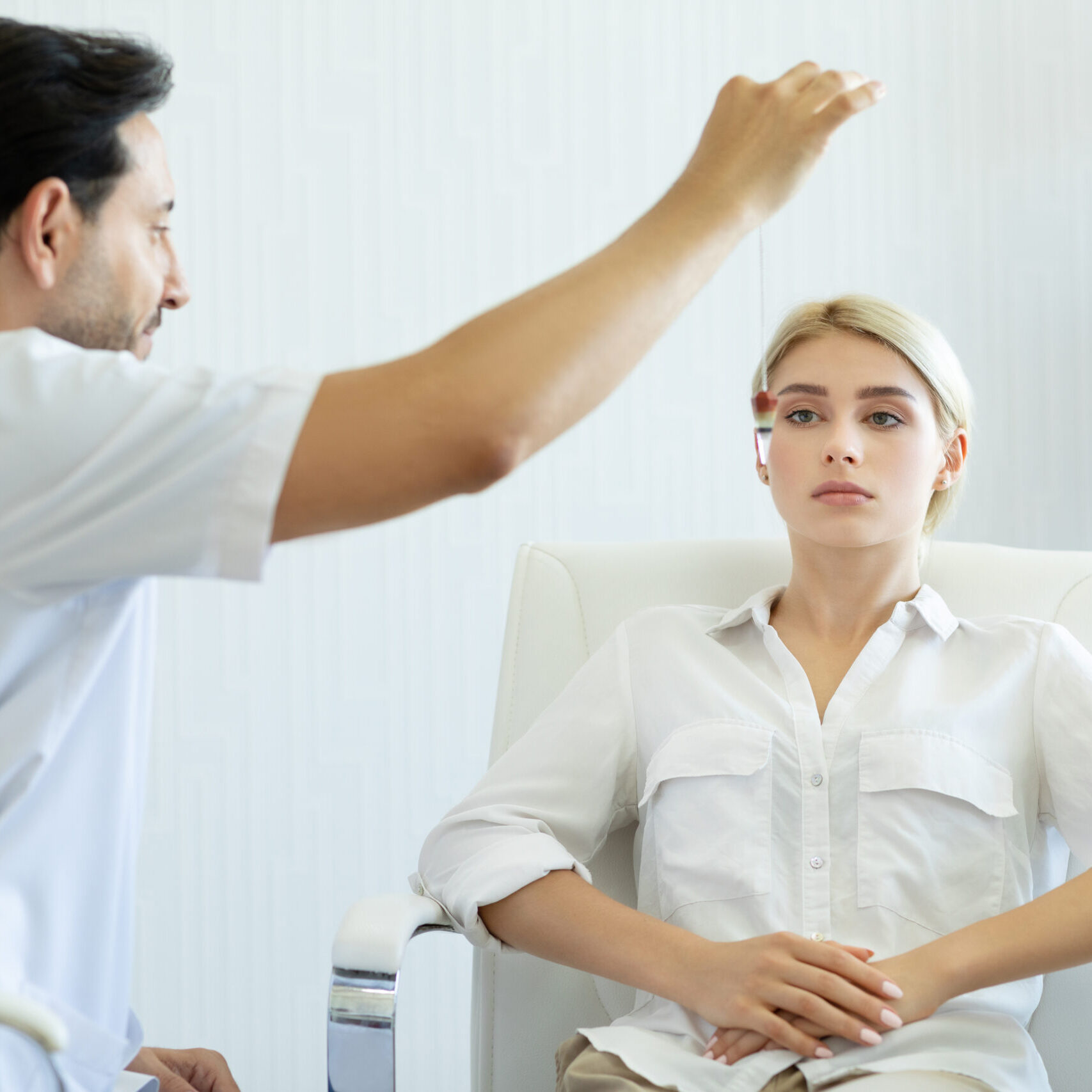 Male therapist using hypnosis therapy on young woman